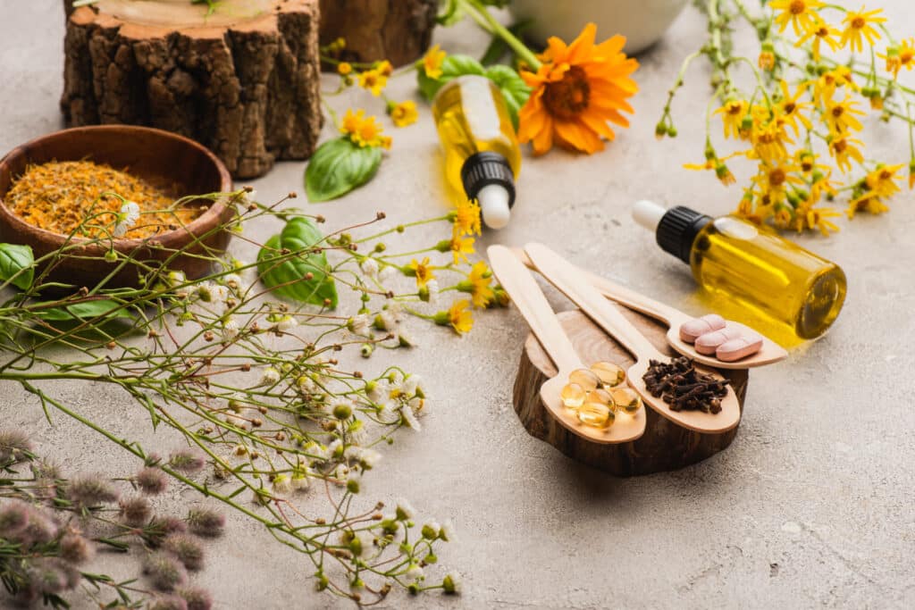 Naturopathic Medicine​ - selective focus of wildflowers, herbs, bottles and pills in wood