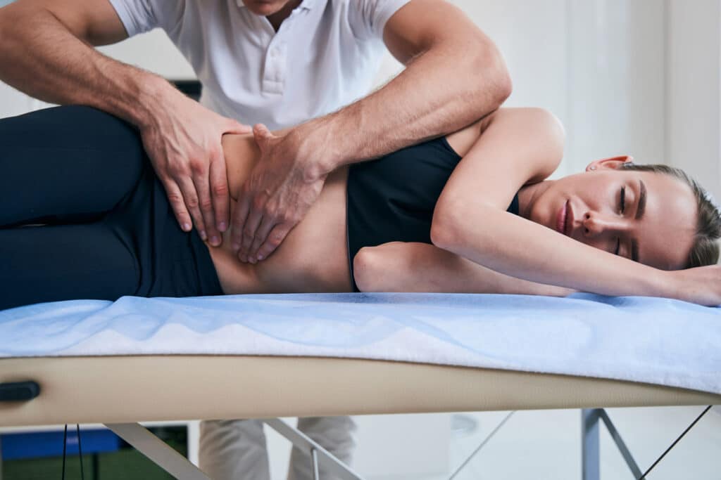 Chiropractic Care​ - Chiropractor working with woman stomach in medical office
